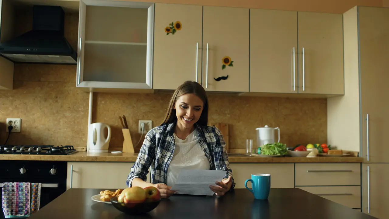A woman reading a letter in her kitchen